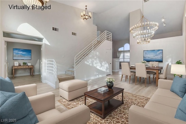 living area featuring a notable chandelier, stairway, high vaulted ceiling, and visible vents