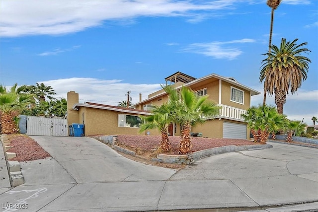 view of front facade featuring an attached garage, a gate, concrete driveway, and stucco siding