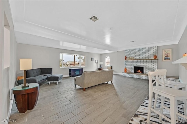 living room with baseboards, a fireplace, visible vents, and wood finish floors