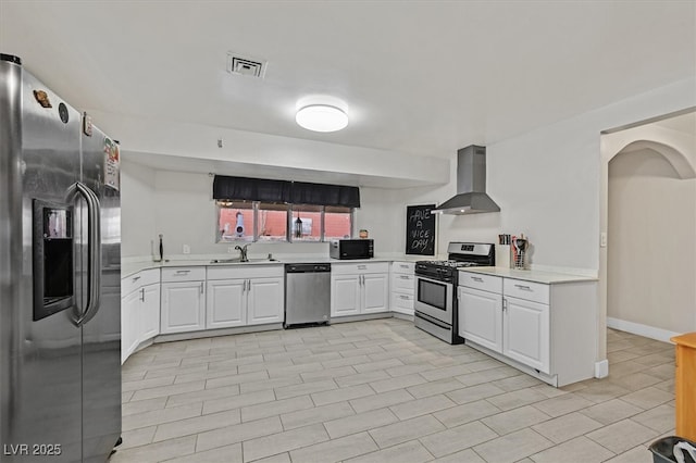 kitchen featuring stainless steel appliances, light countertops, visible vents, a sink, and wall chimney exhaust hood