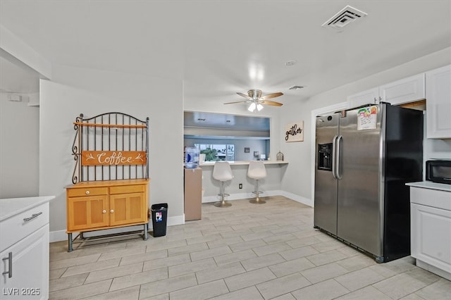 kitchen with visible vents, ceiling fan, light countertops, black microwave, and stainless steel refrigerator with ice dispenser