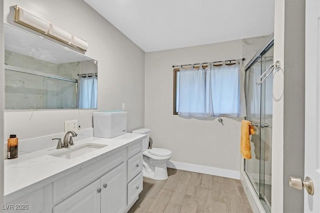 full bathroom featuring toilet, a shower stall, vanity, wood finished floors, and baseboards