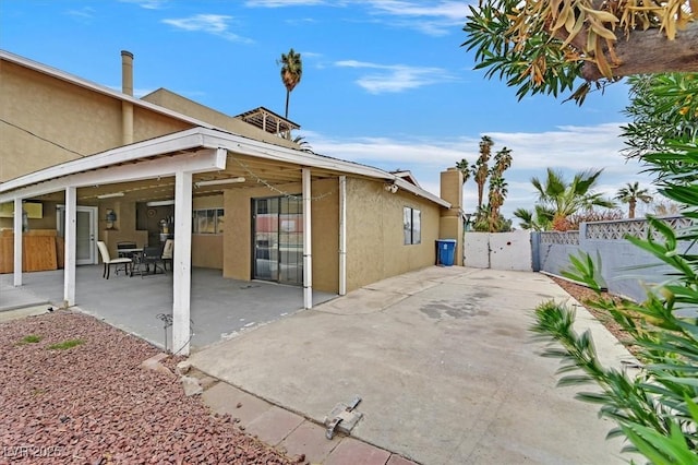 rear view of house with fence, a patio, and stucco siding