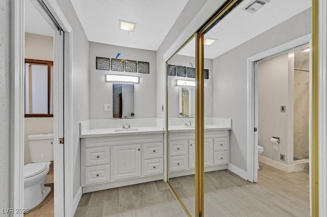 bathroom with visible vents, vanity, toilet, and wood finished floors