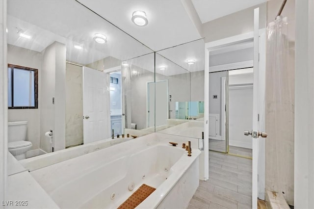 full bathroom with toilet, a tub with jets, and vanity