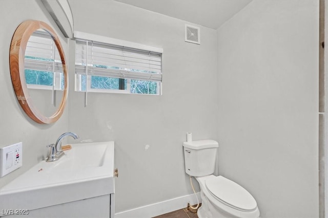 half bathroom featuring toilet, baseboards, visible vents, and vanity