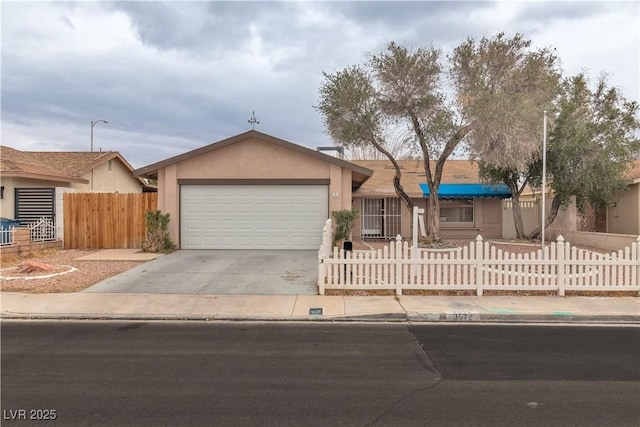 ranch-style home with an attached garage, driveway, a fenced front yard, and stucco siding