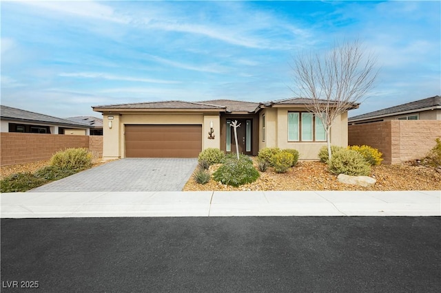 view of front of home featuring a garage, decorative driveway, fence, and stucco siding