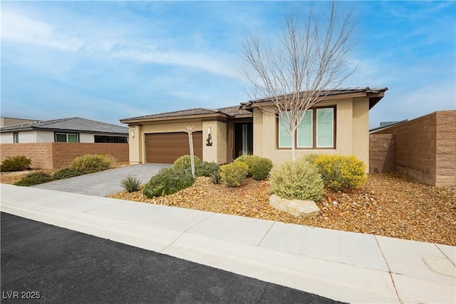 view of front of house with driveway, an attached garage, fence, and stucco siding