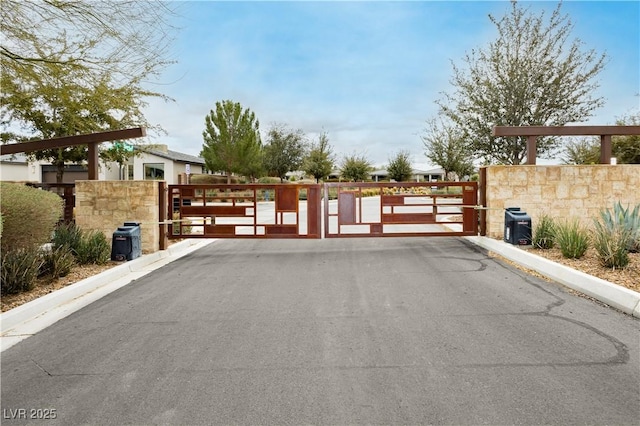 view of street with a gate, a gated entry, and curbs