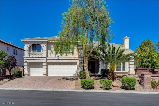 view of front of home featuring a garage, fence, decorative driveway, stucco siding, and a chimney