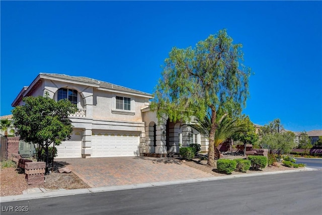 view of front of property with decorative driveway, an attached garage, and stucco siding