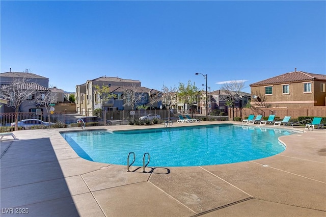 pool with a patio, fence, and a residential view