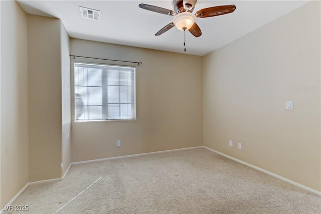 carpeted spare room featuring ceiling fan, visible vents, and baseboards