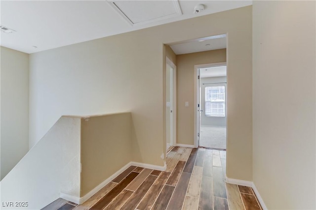 hall featuring an upstairs landing, visible vents, baseboards, and wood finish floors