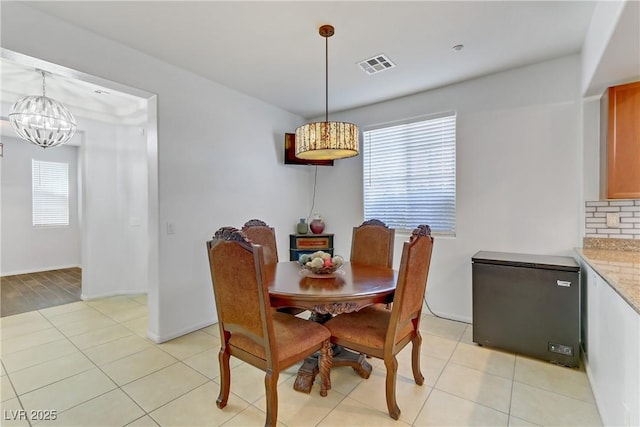 dining room featuring baseboards, light tile patterned flooring, visible vents, and a notable chandelier