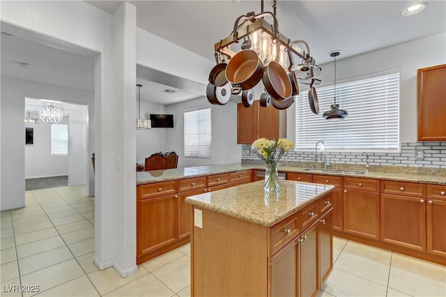 kitchen with a healthy amount of sunlight, a sink, backsplash, and light stone countertops