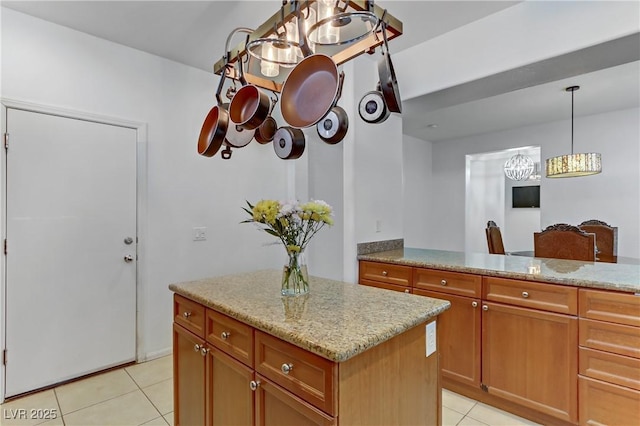 kitchen with light stone counters, hanging light fixtures, and light tile patterned floors