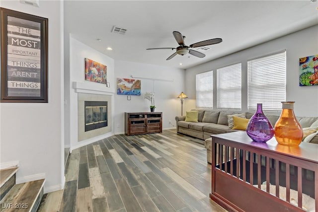 living area with a fireplace, recessed lighting, visible vents, ceiling fan, and wood finished floors