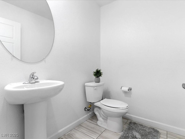 bathroom with a sink, toilet, and baseboards