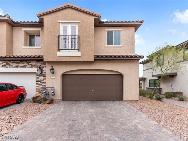 view of front of house with decorative driveway, an attached garage, and stucco siding