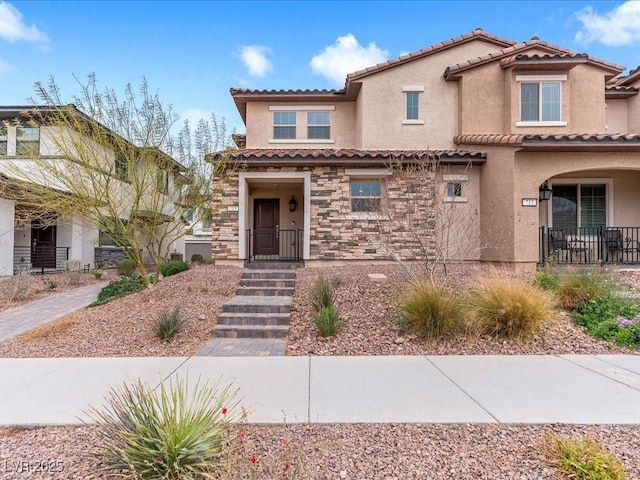 view of front of property with a tiled roof, stone siding, and stucco siding