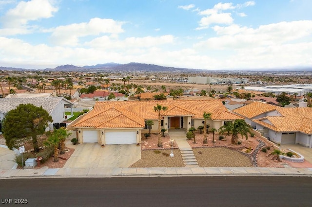 mediterranean / spanish-style house featuring a mountain view, a garage, a tiled roof, concrete driveway, and stucco siding