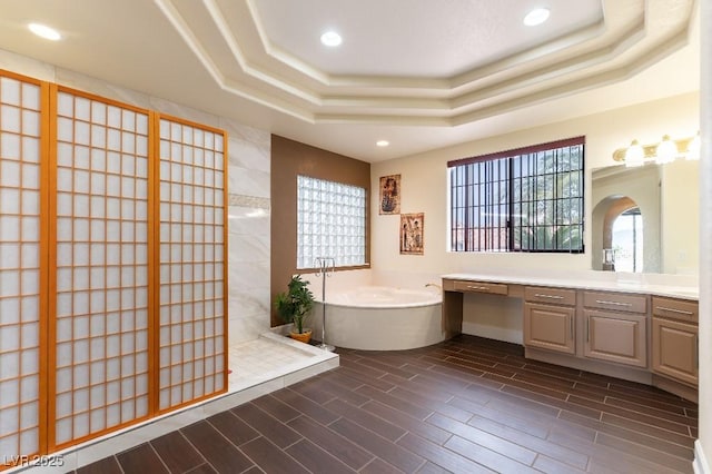 full bathroom with a garden tub, wood finish floors, a raised ceiling, and a walk in shower