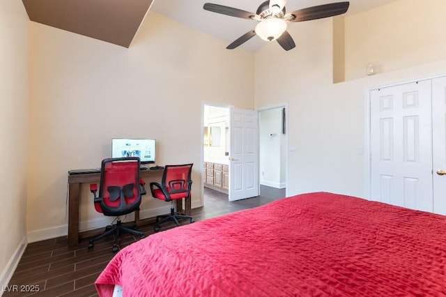 bedroom with ceiling fan, connected bathroom, a towering ceiling, baseboards, and dark wood-style floors