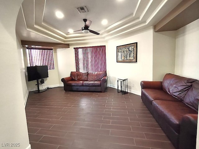 living room featuring baseboards, ceiling fan, visible vents, and a tray ceiling