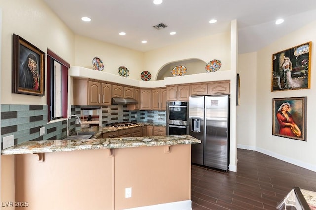 kitchen with light stone counters, visible vents, appliances with stainless steel finishes, a sink, and a peninsula