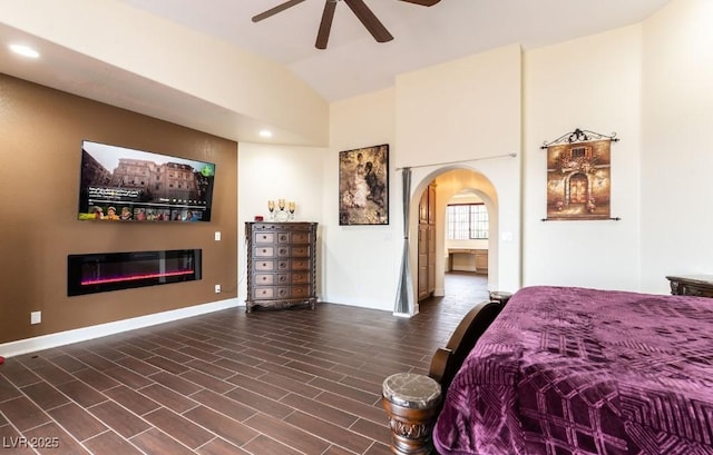 bedroom featuring recessed lighting, arched walkways, vaulted ceiling, and a glass covered fireplace