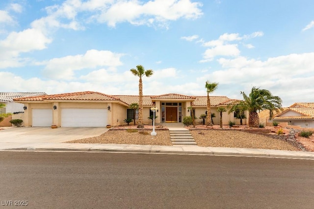 mediterranean / spanish house with driveway, a tiled roof, an attached garage, and stucco siding