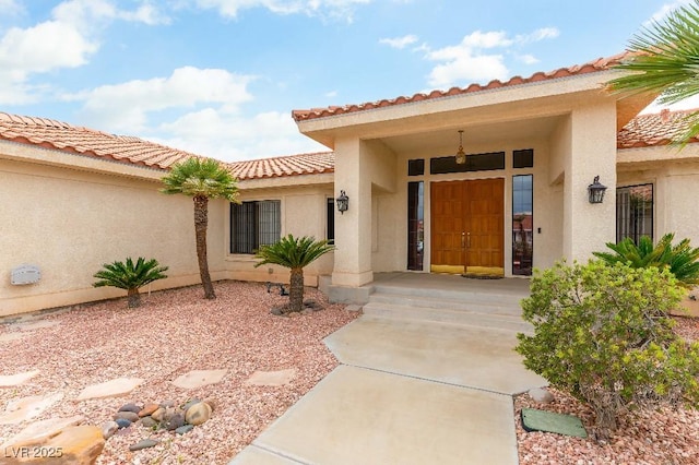 property entrance with a tile roof and stucco siding