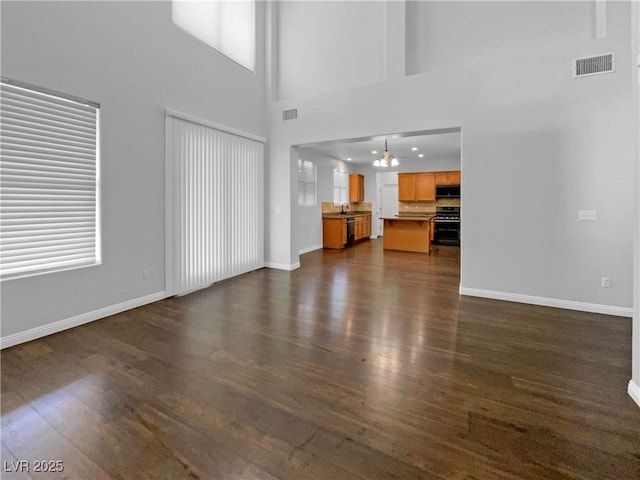 unfurnished living room with dark wood-style floors, visible vents, and baseboards