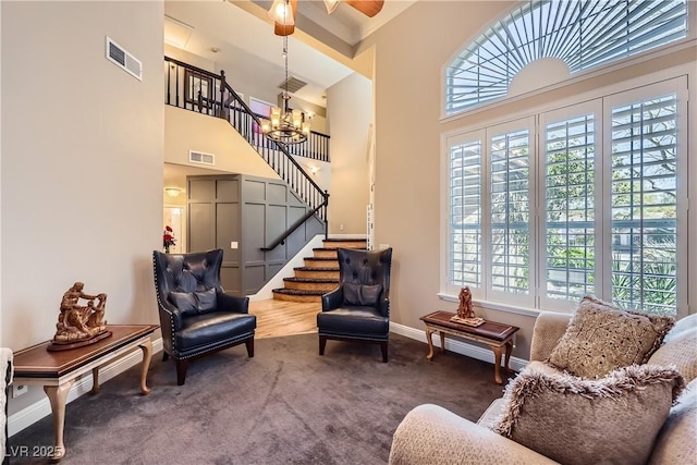 sitting room featuring carpet floors, a high ceiling, stairway, and visible vents