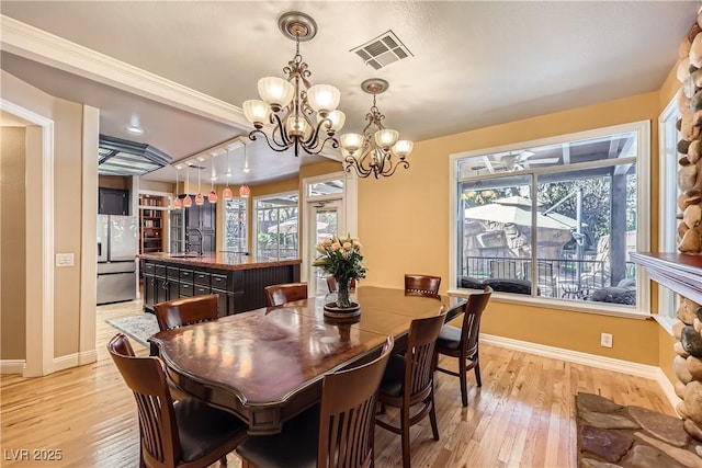 dining space with a healthy amount of sunlight, light wood-style flooring, visible vents, and baseboards