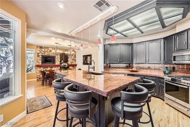 kitchen featuring visible vents, decorative backsplash, a breakfast bar area, appliances with stainless steel finishes, and a sink