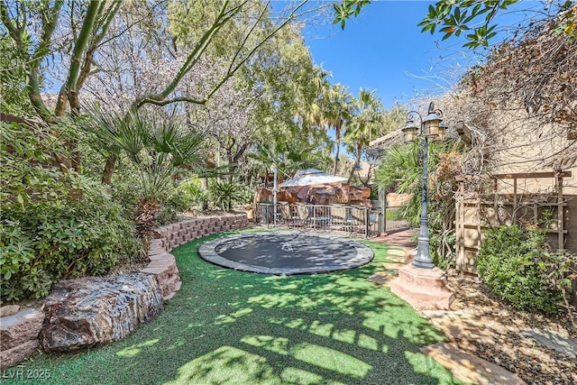 view of yard with a trampoline and fence