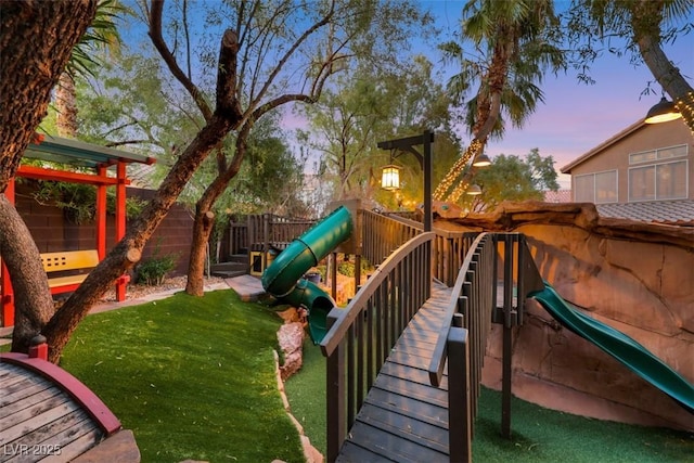 view of jungle gym with a lawn and fence