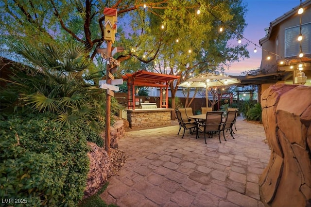 patio terrace at dusk with outdoor dining space, fence, and area for grilling