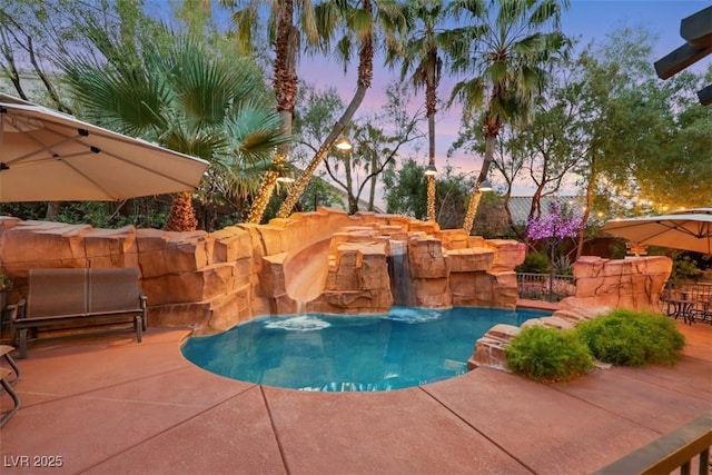 pool at dusk featuring a patio area and a fenced in pool