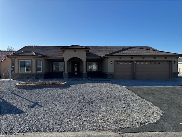 view of front of home featuring stone siding, aphalt driveway, an attached garage, and stucco siding