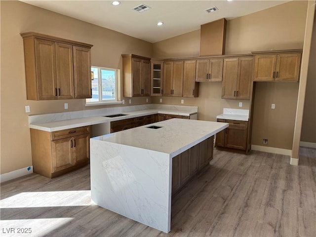 kitchen with light wood-type flooring, visible vents, and brown cabinets