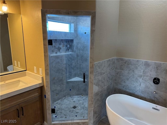 bathroom featuring a stall shower, vanity, tile walls, and a soaking tub