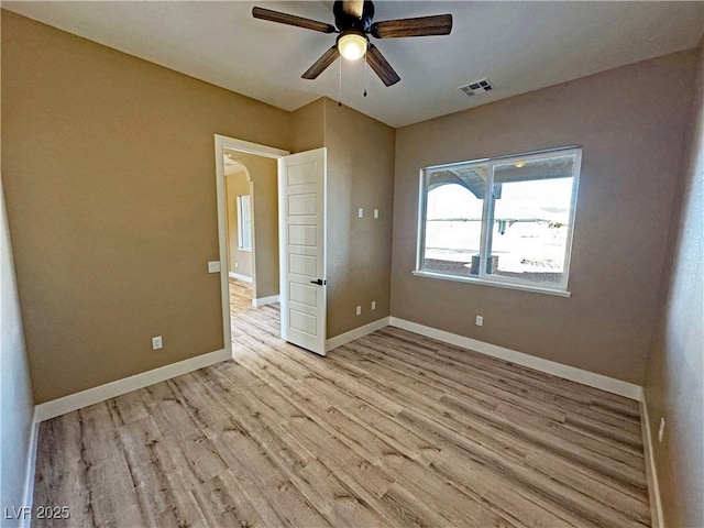 3080 S Prairie Ave, Pahrump, NV 89048 - unfurnished bedroom featuring light wood-style floors, baseboards, arched walkways, and a ceiling fan