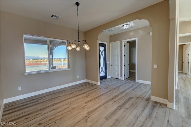 3080 S Prairie Ave, Pahrump, NV 89048 - unfurnished dining area with light wood-style floors, visible vents, baseboards, and arched walkways