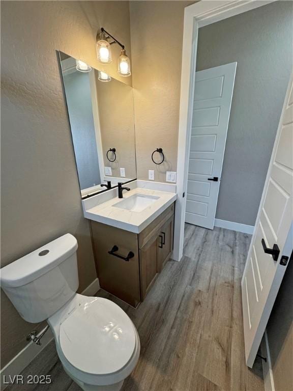 3080 S Prairie Ave, Pahrump, NV 89048 - bathroom featuring wood finished floors, toilet, vanity, and baseboards