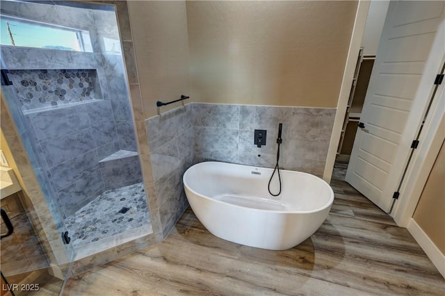 3080 S Prairie Ave, Pahrump, NV 89048 - bathroom featuring tile walls, wood finished floors, wainscoting, a soaking tub, and a tile shower