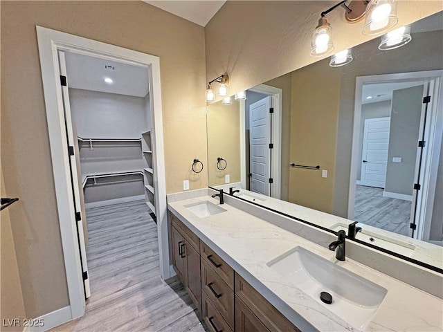 3080 S Prairie Ave, Pahrump, NV 89048 - full bathroom with double vanity, wood finished floors, a walk in closet, and a sink